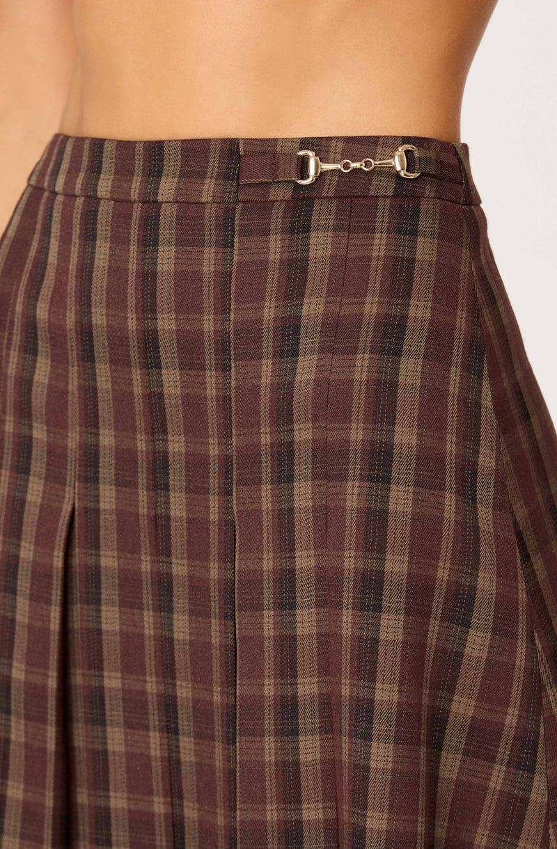 The image shows a high-waisted skirt with a plaid pattern in shades of brown, beige, and black. The skirt features a subtle pleat on the front and has a small metal clasp detail at the waistband.