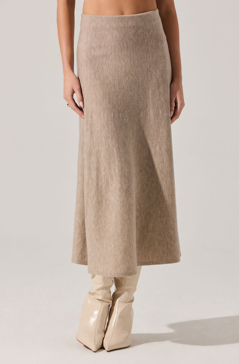 A beige, high-waisted, ankle-length skirt made of a soft, wool-like fabric. The skirt has a simple, straight silhouette with no visible embellishments or patterns. The model is also wearing knee-high, glossy, cream-colored boots.