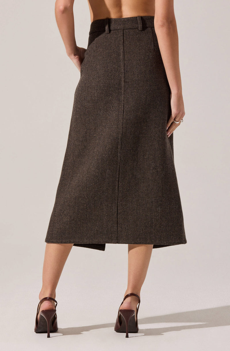 A woman is wearing a high-waisted, ankle-length skirt with a subtle checkered pattern in shades of brown and black. The skirt has a straight silhouette and features belt loops at the waistband. She is also wearing dark brown high-heeled open-toe shoes with ankle straps.