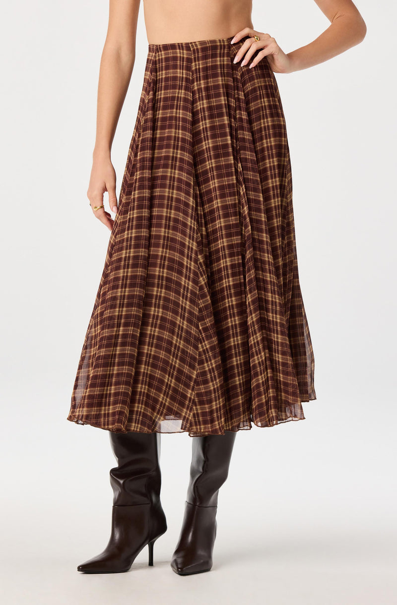 Brown plaid long skirt with pleats, paired with black high-heeled boots.