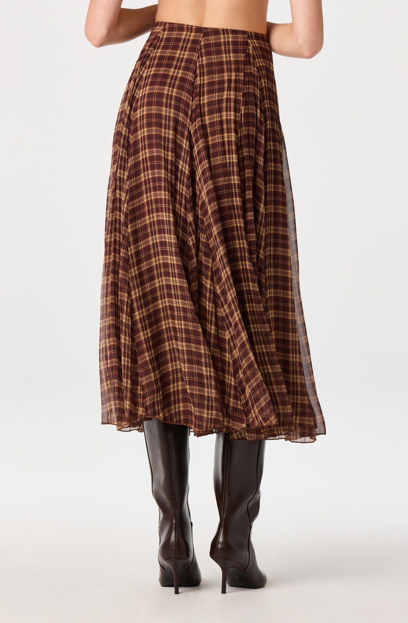 Plaid brown and yellow midi skirt with pleats, paired with black knee-high boots.