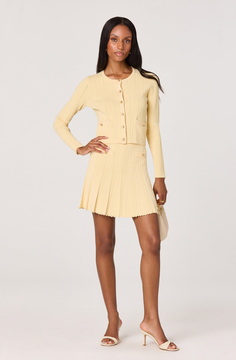 Light yellow cardigan and matching pleated skirt set with buttons.