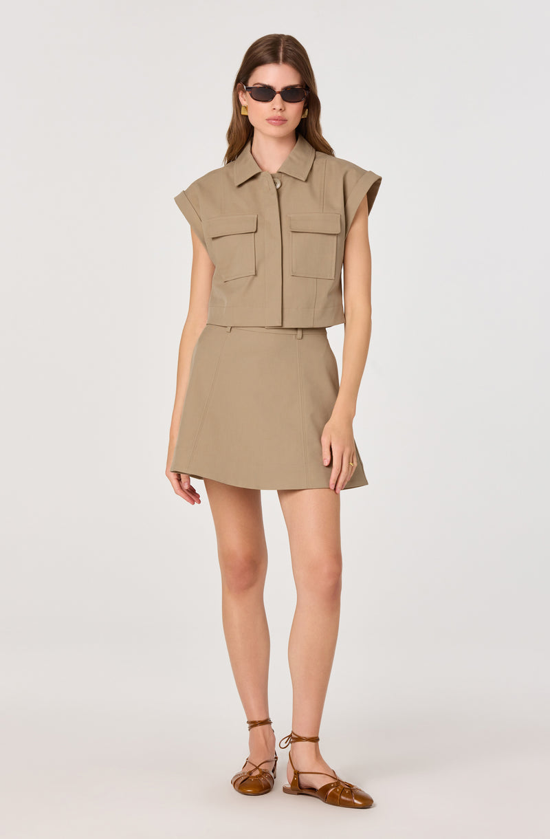 Beige sleeveless cropped jacket with flap pockets and a matching A-line skirt.