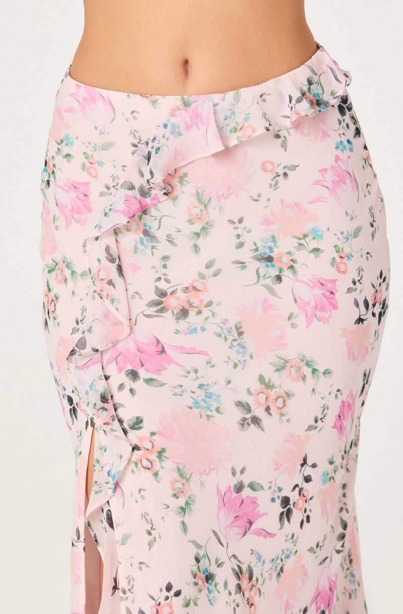 Close-up of a woman's floral pink and white skirt with ruffles and a side slit.