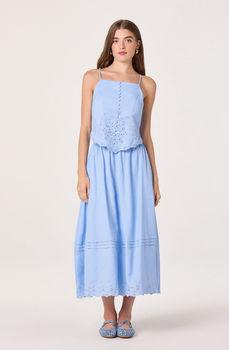 Woman wearing a light blue, spaghetti strap top with eyelet hem and a matching long skirt.