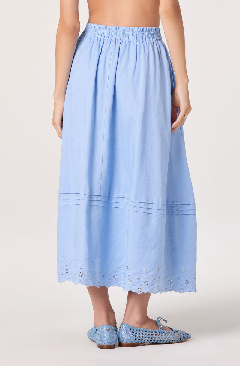 Light blue ankle-length skirt with embroidery and eyelet details at the hem, paired with matching shoes.