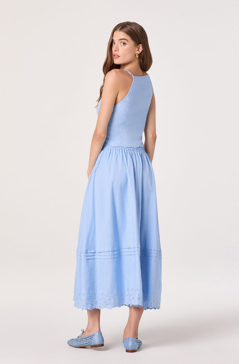 Woman in light blue tank top and matching long skirt with eyelet hem and lace details.