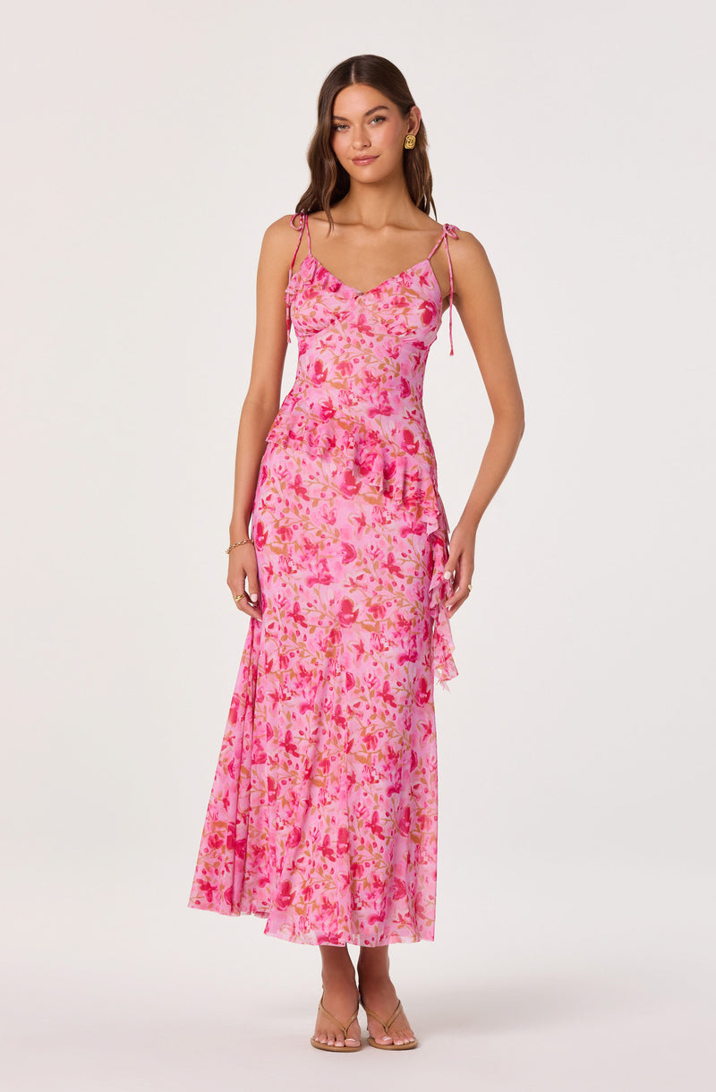 Woman in a pink floral sleeveless maxi dress with spaghetti straps and ruffle details.