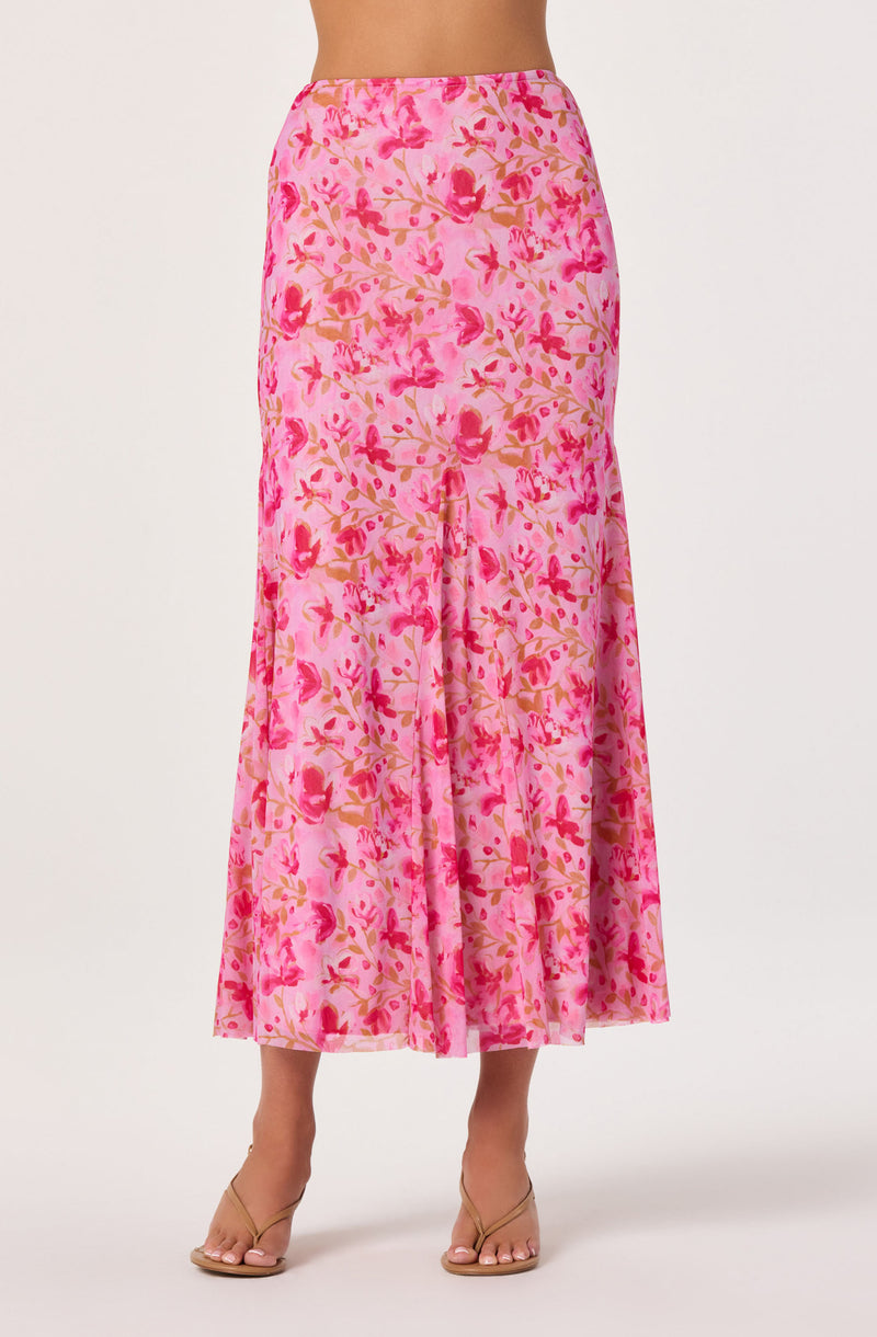 Pink floral printed maxi skirt with a flowy silhouette, paired with nude sandals.