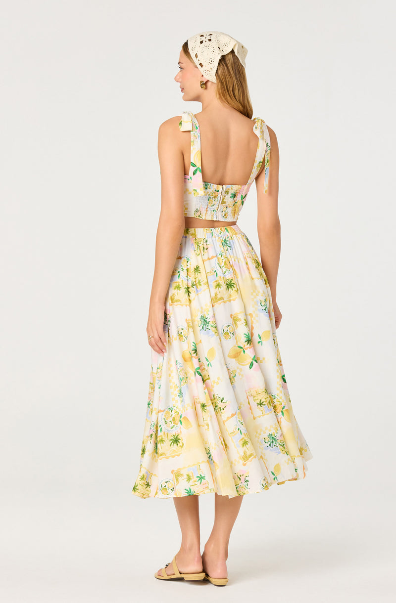 Woman in a colorful, tropical print two-piece outfit with a cropped top and mid-length skirt.
