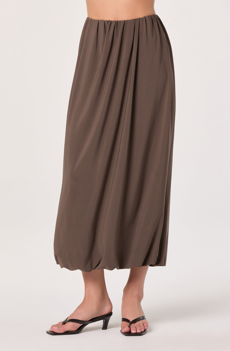 Brown gathered maxi skirt with elastic waistband, paired with black high-heeled sandals.
