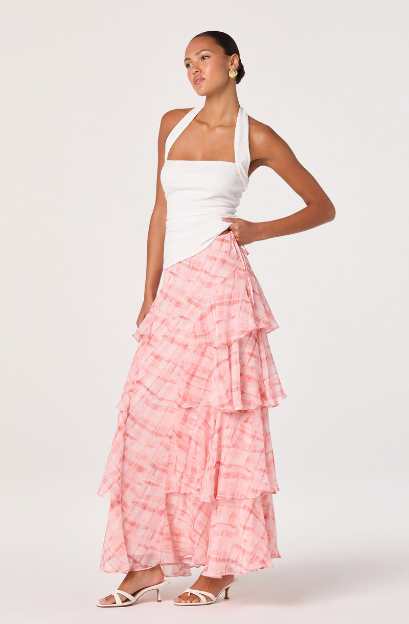 Woman wearing a white sleeveless top with wide straps and a pink ruffled tiered skirt.