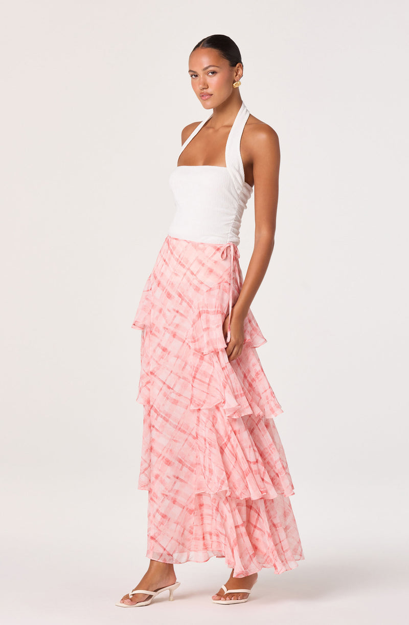 Woman wearing a white sleeveless top with halter style and a pink tiered ruffled skirt.