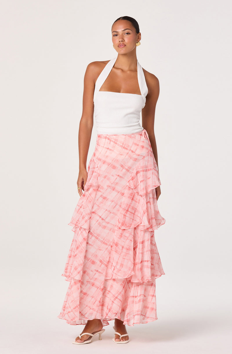 Woman wearing a white halter top and a pink tiered ruffle maxi skirt.