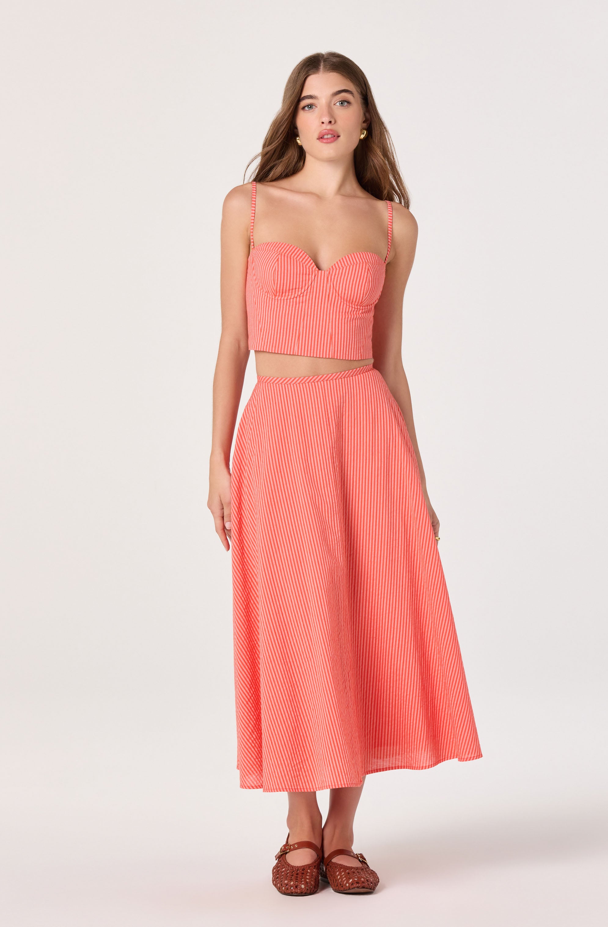 Woman in a coral and white striped matching crop top with spaghetti straps and wide-leg pants.