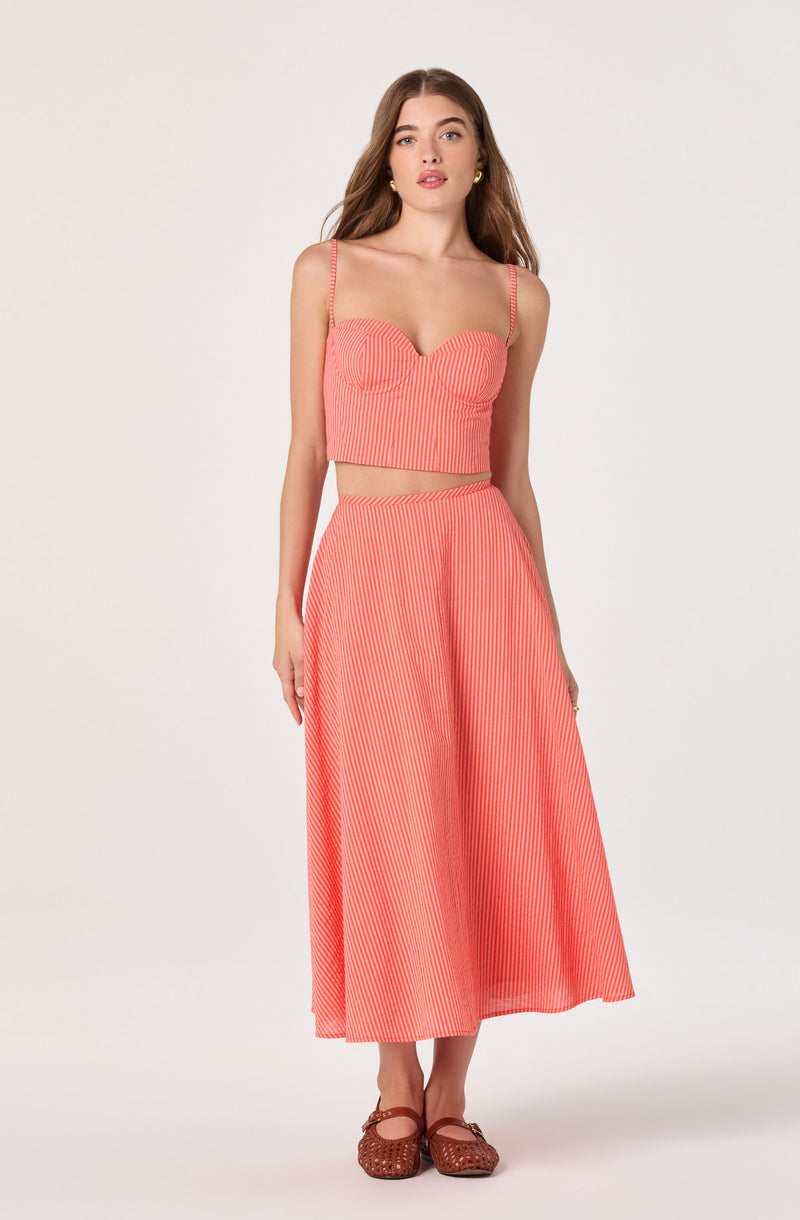 Woman in a coral and white striped matching crop top with spaghetti straps and wide-leg pants.