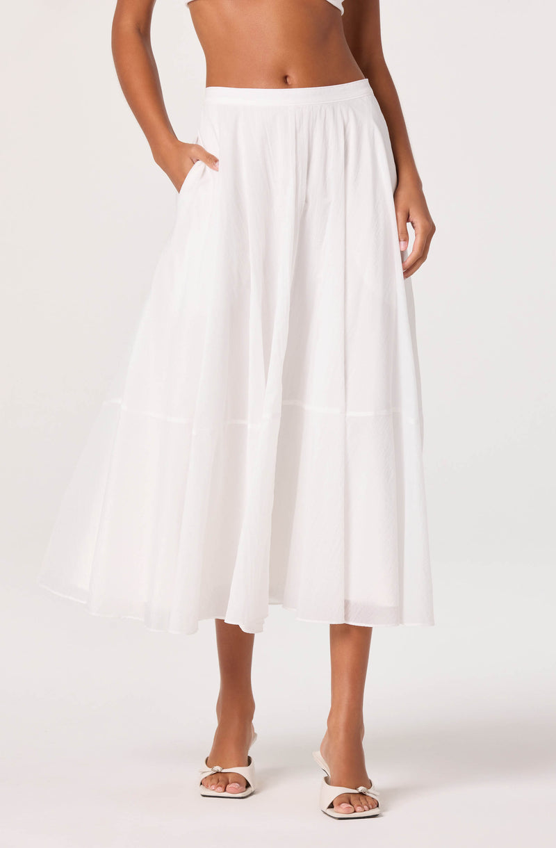 Woman wearing a white, wide-leg, midi skirt with pockets and pleats.