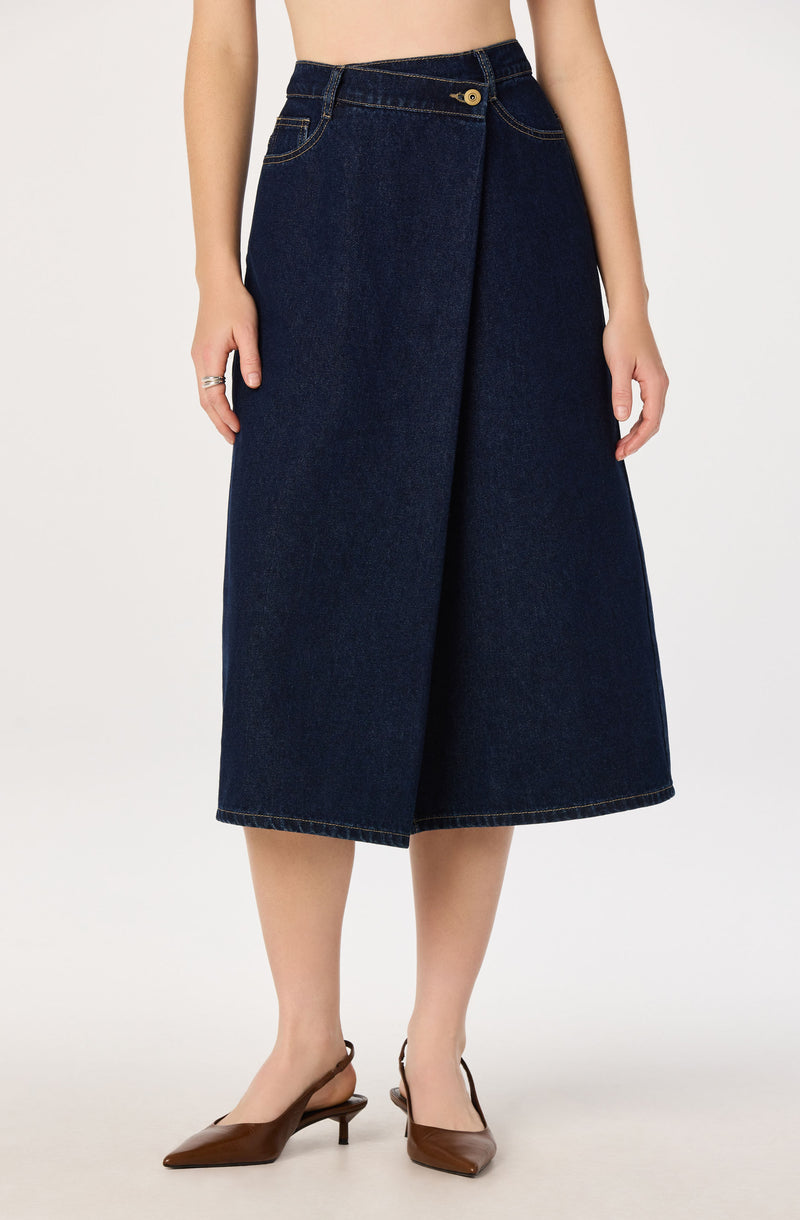 Woman wearing a high-waisted, dark denim, wide-leg midi skirt and brown pointed-toe heels.