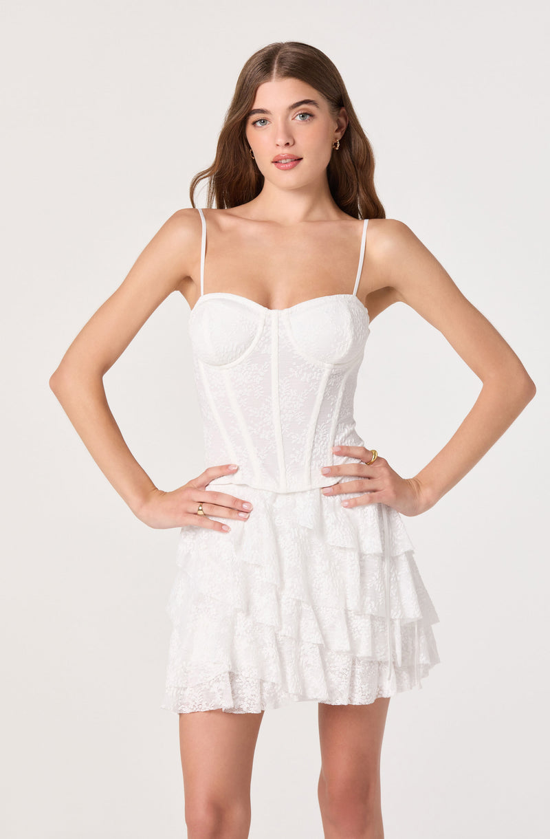 Woman in white lace dress with spaghetti straps and tiered ruffled skirt.