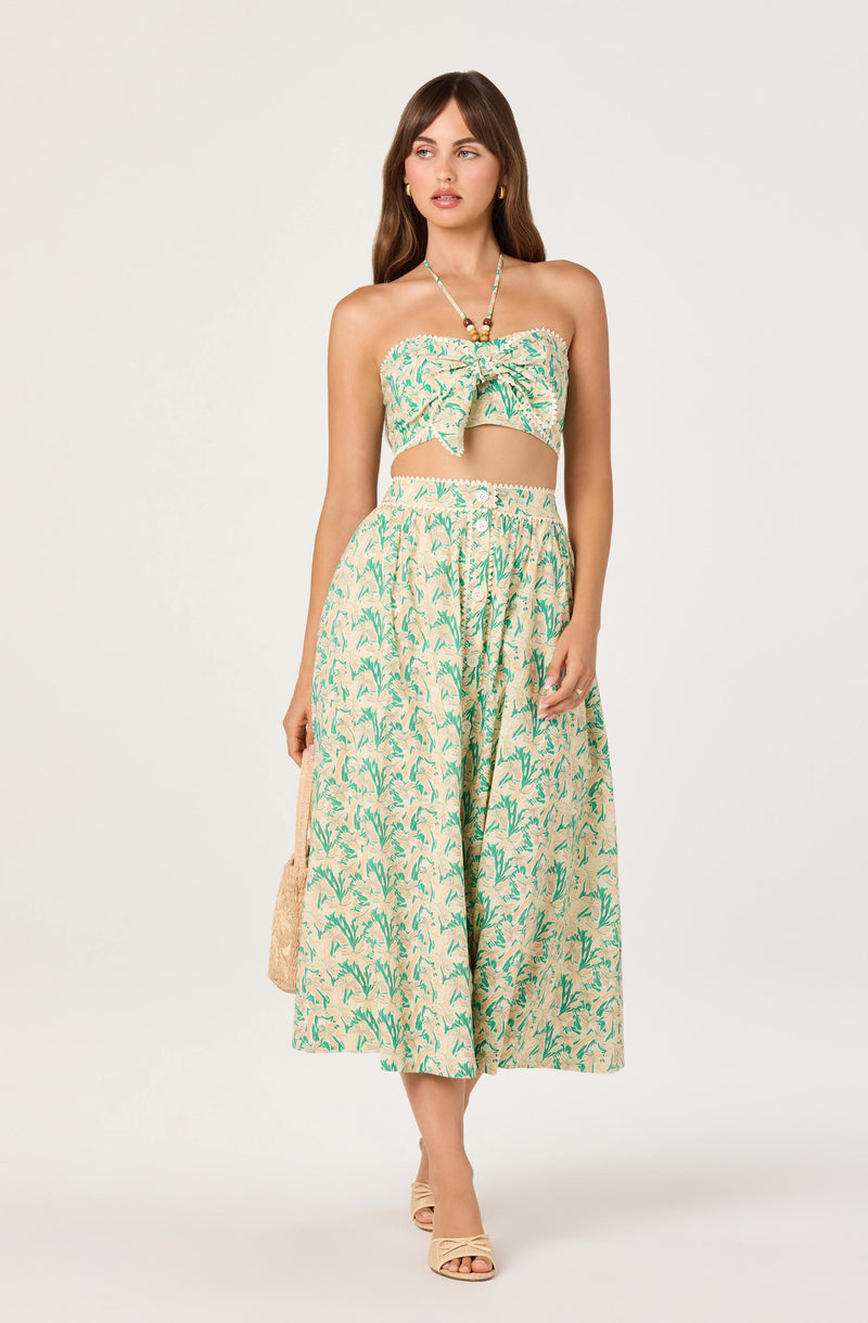 Woman wearing a strapless green and beige floral top with matching wide-leg pants.