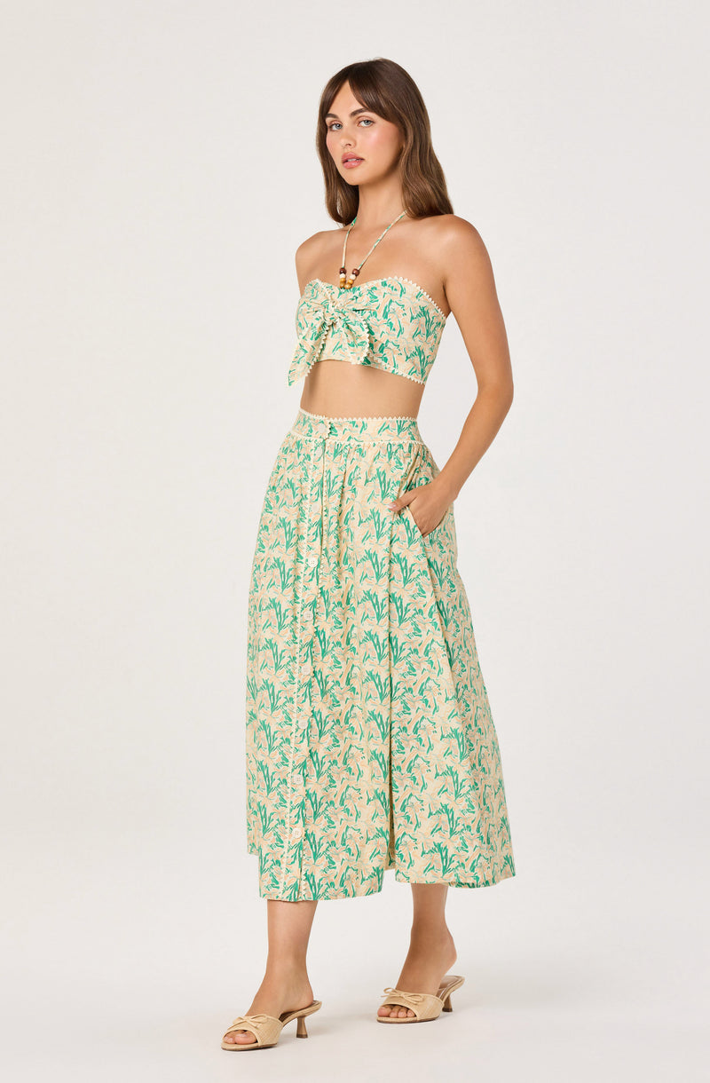 Woman wearing a strapless, floral print crop top and matching wide-leg pants in beige and green.