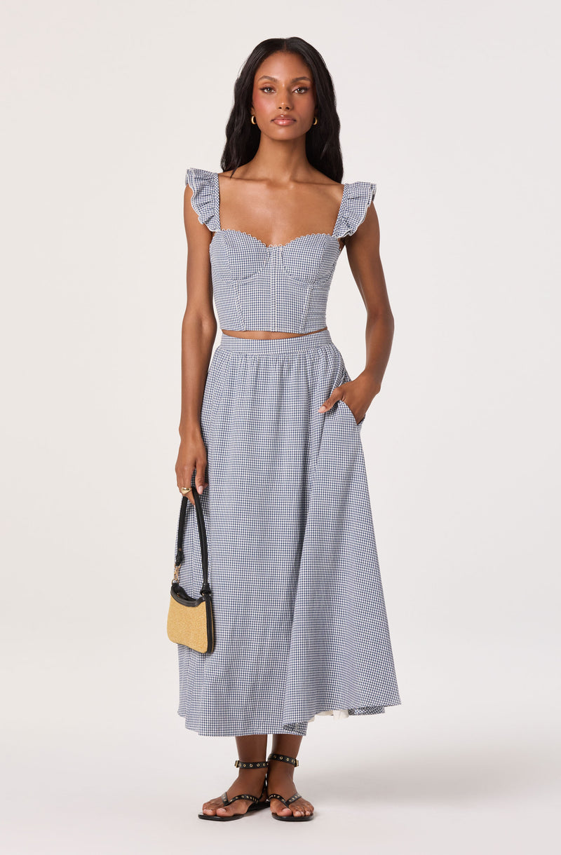 Woman in a blue and white checkered crop top with ruffled sleeves and a matching long skirt.