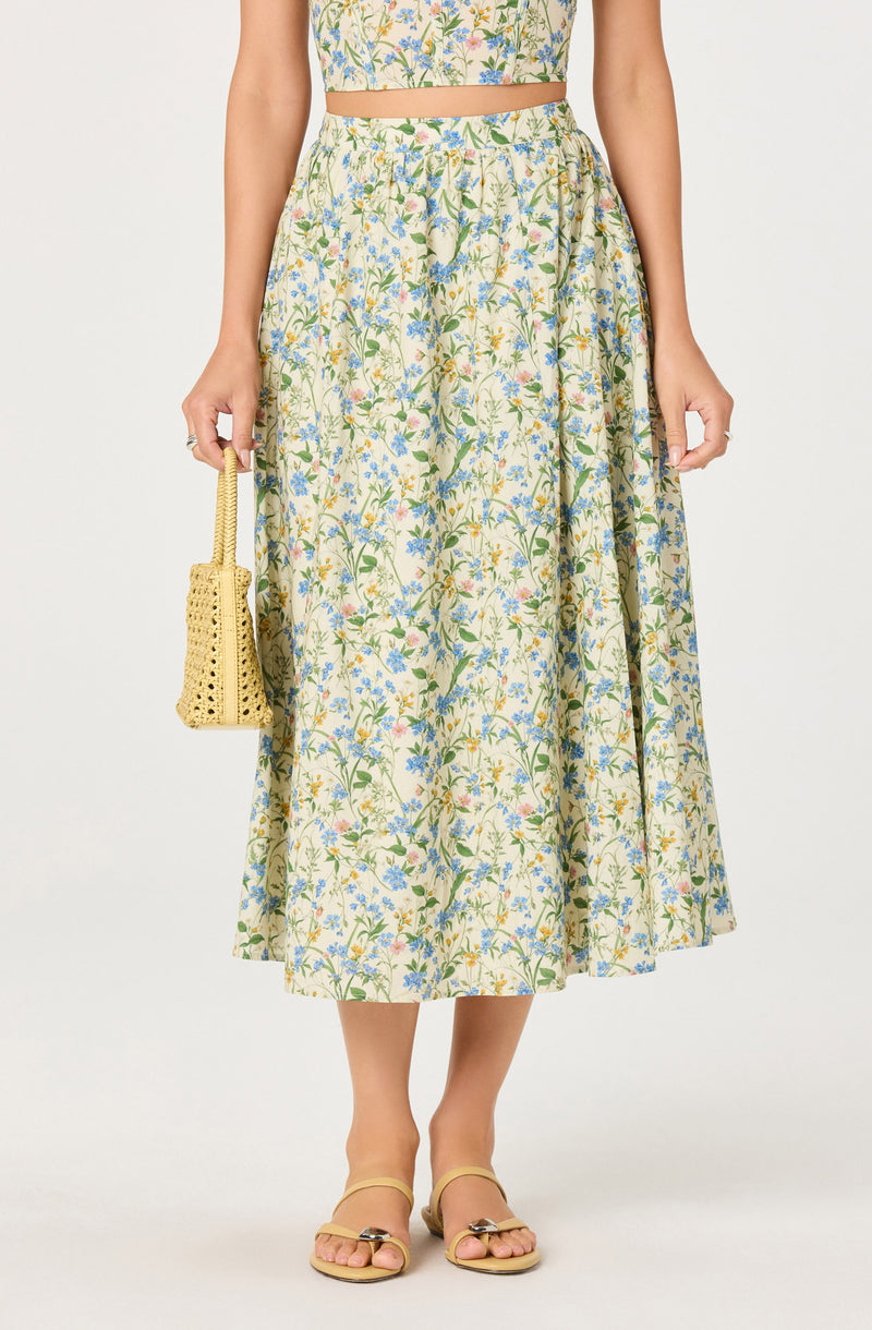 Light-colored floral crop top with matching high-waisted, flowy skirt, and beige sandals.