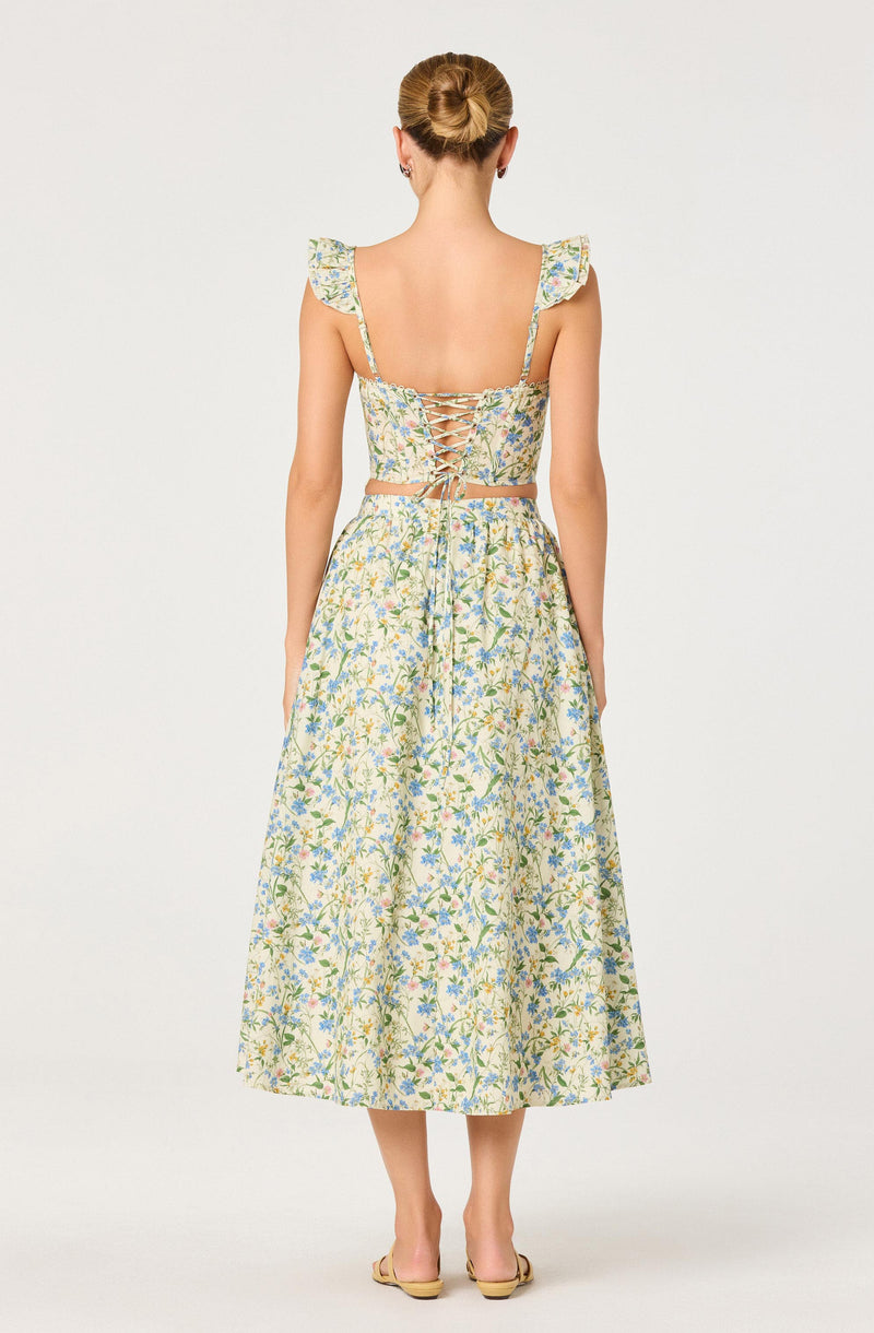 Back view of a woman wearing a floral two-piece outfit with ruffled shoulder straps and lace-up back.