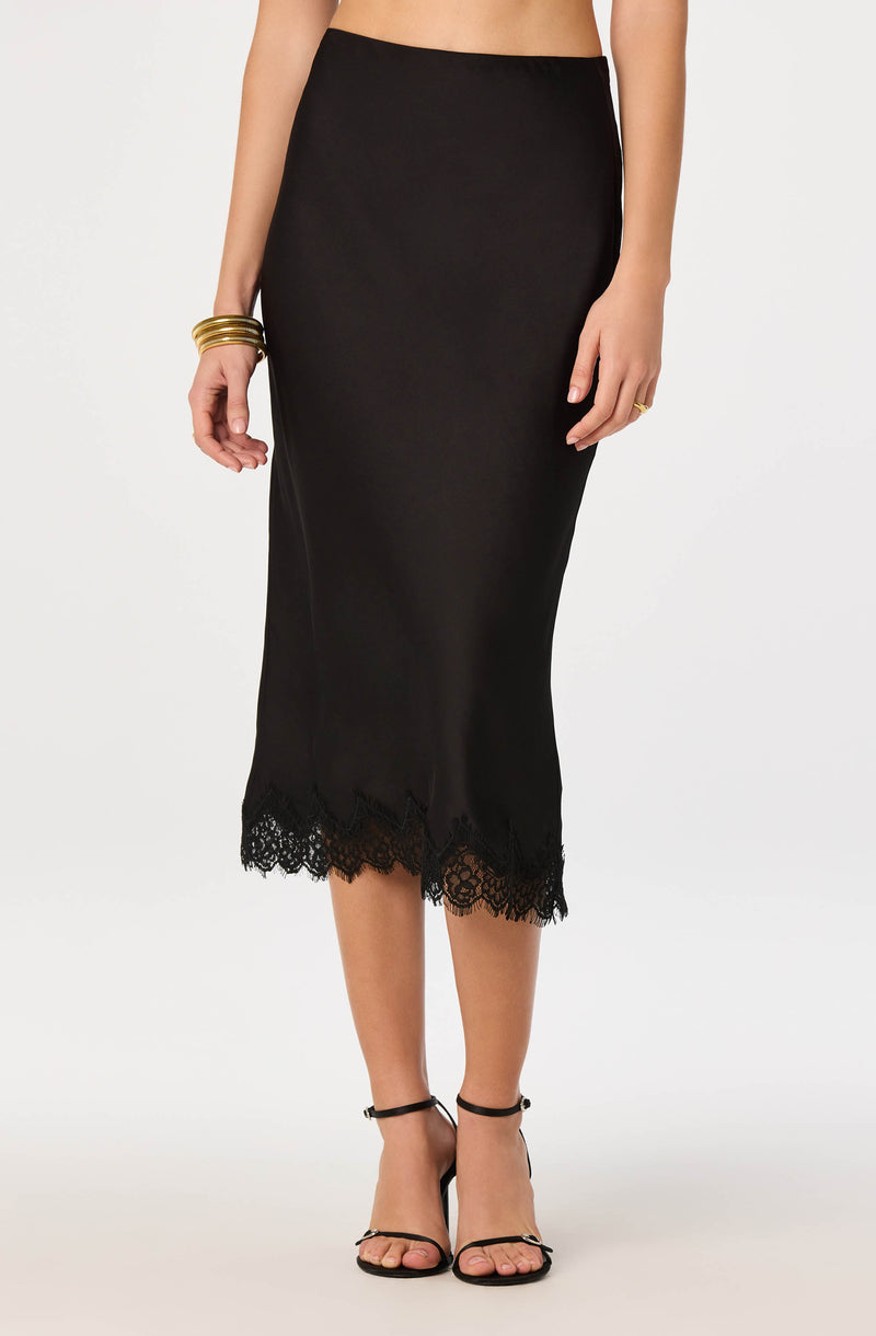 Black midi skirt with lace hem and satin-like fabric, paired with black ankle-strap heels.