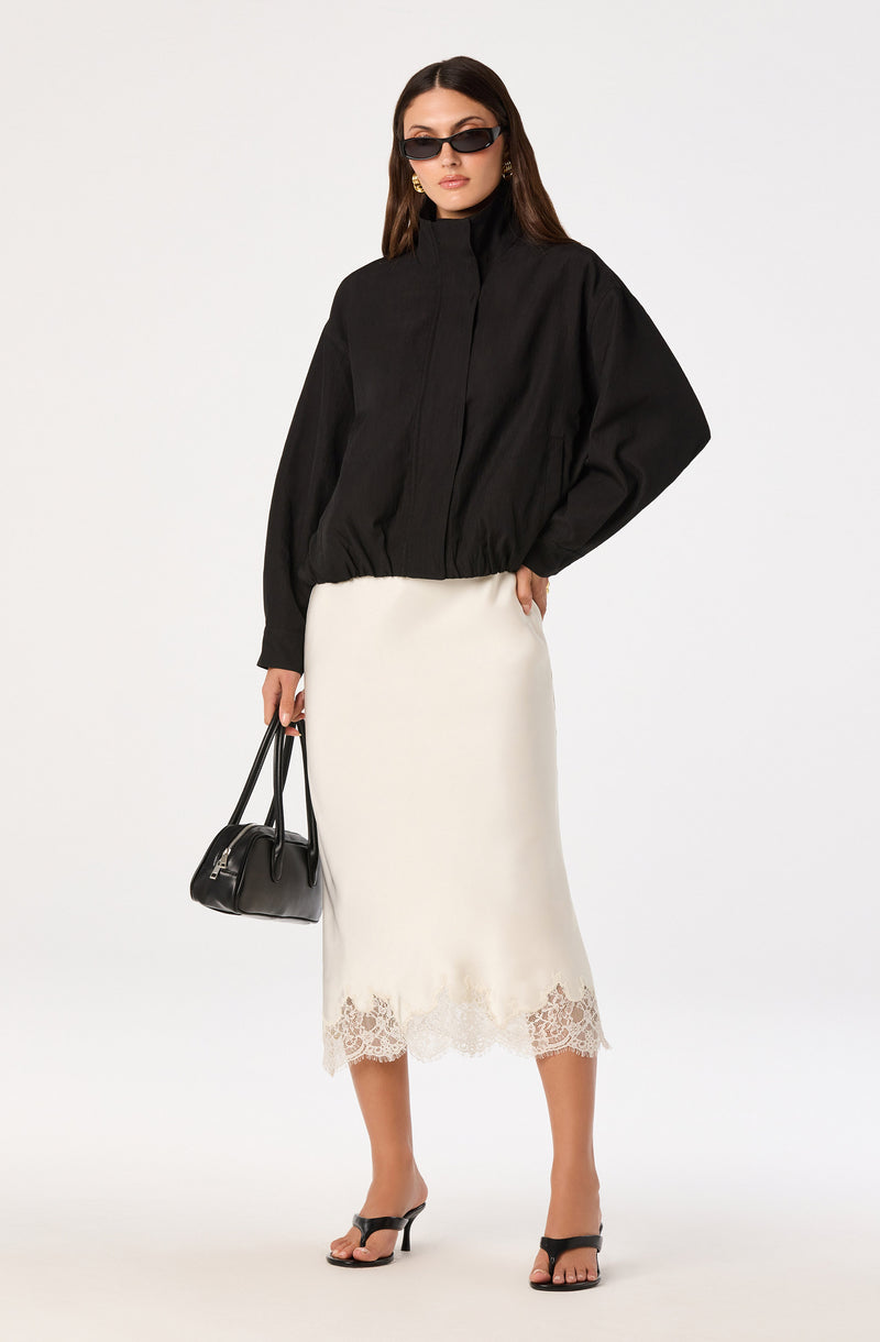 Black oversized jacket, white lace-hem midi skirt, black open-toe heels, black handbag, and sunglasses.