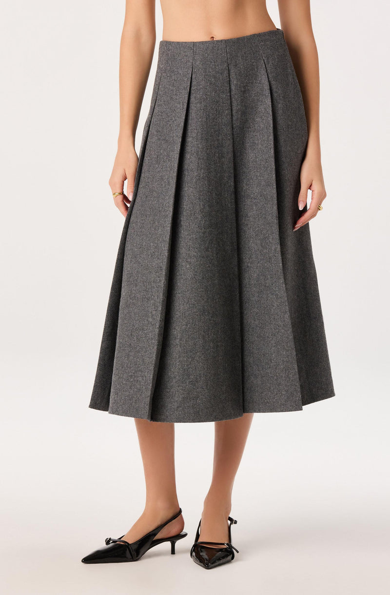 Gray pleated midi skirt with front pleats and side trims, worn with black pointed heels.