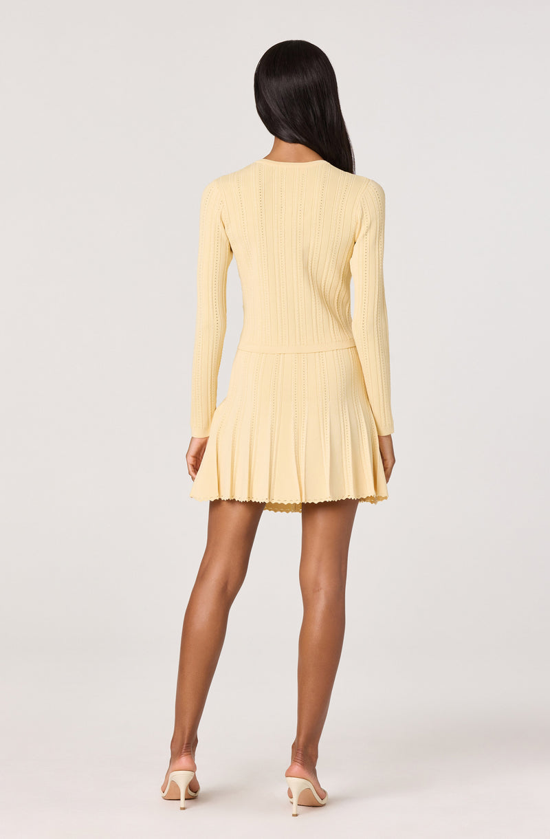 Light yellow knitted dress with long sleeves and a pleated skirt.