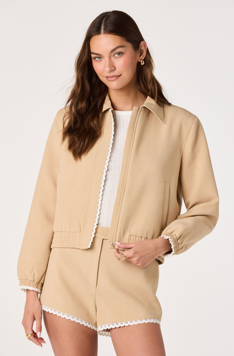 Woman wearing a beige jacket with elastic cuffs and matching shorts with lace trim.