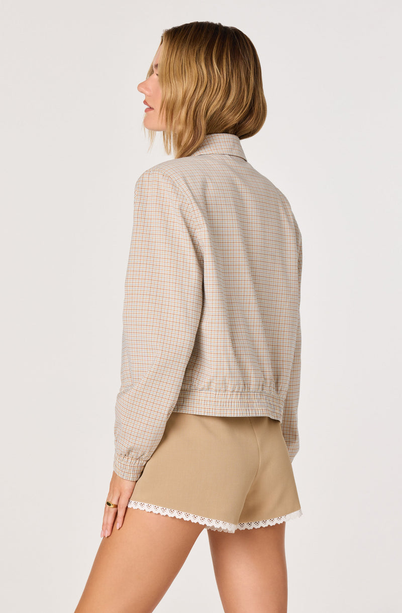 Woman wearing a plaid jacket and beige shorts with white lace trim.