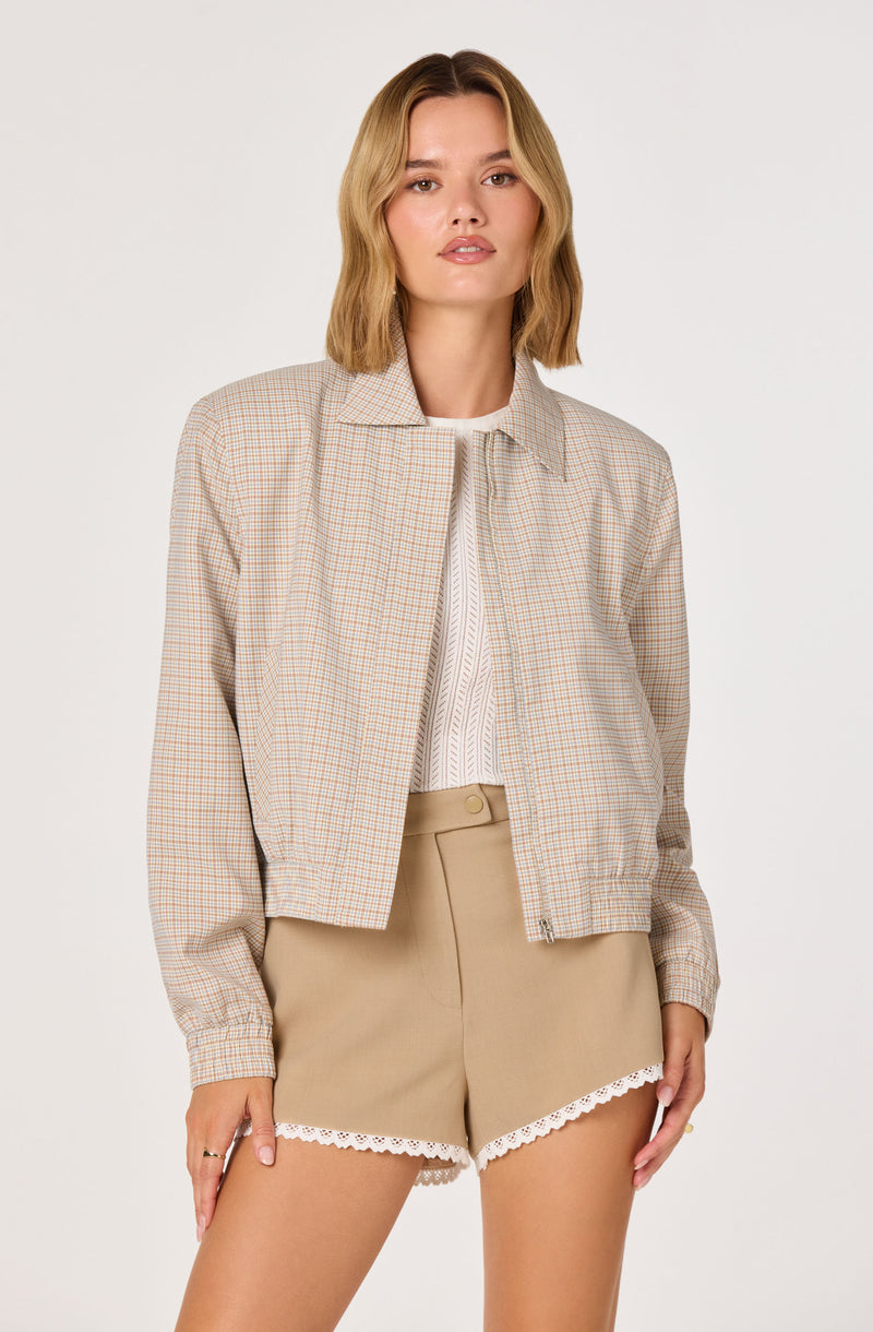 Woman wearing a beige plaid jacket and matching shorts with white lace trim.