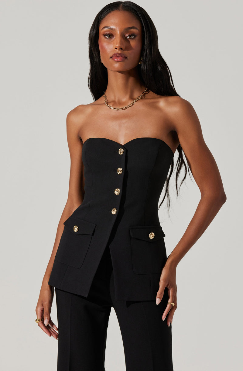 A woman is wearing a strapless black blazer with gold buttons down the front and on the two flap pockets near the hips.