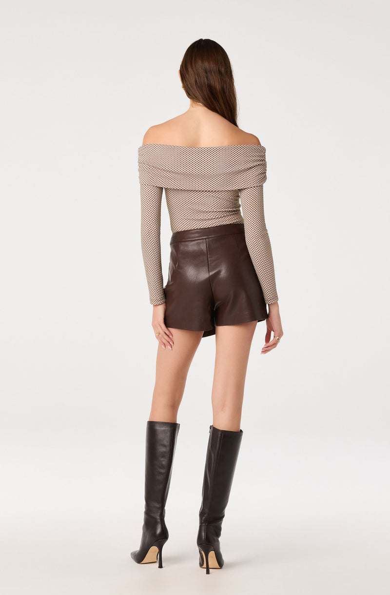 Off-shoulder pattern top with long sleeves, high-waisted leather shorts, and knee-high black boots.