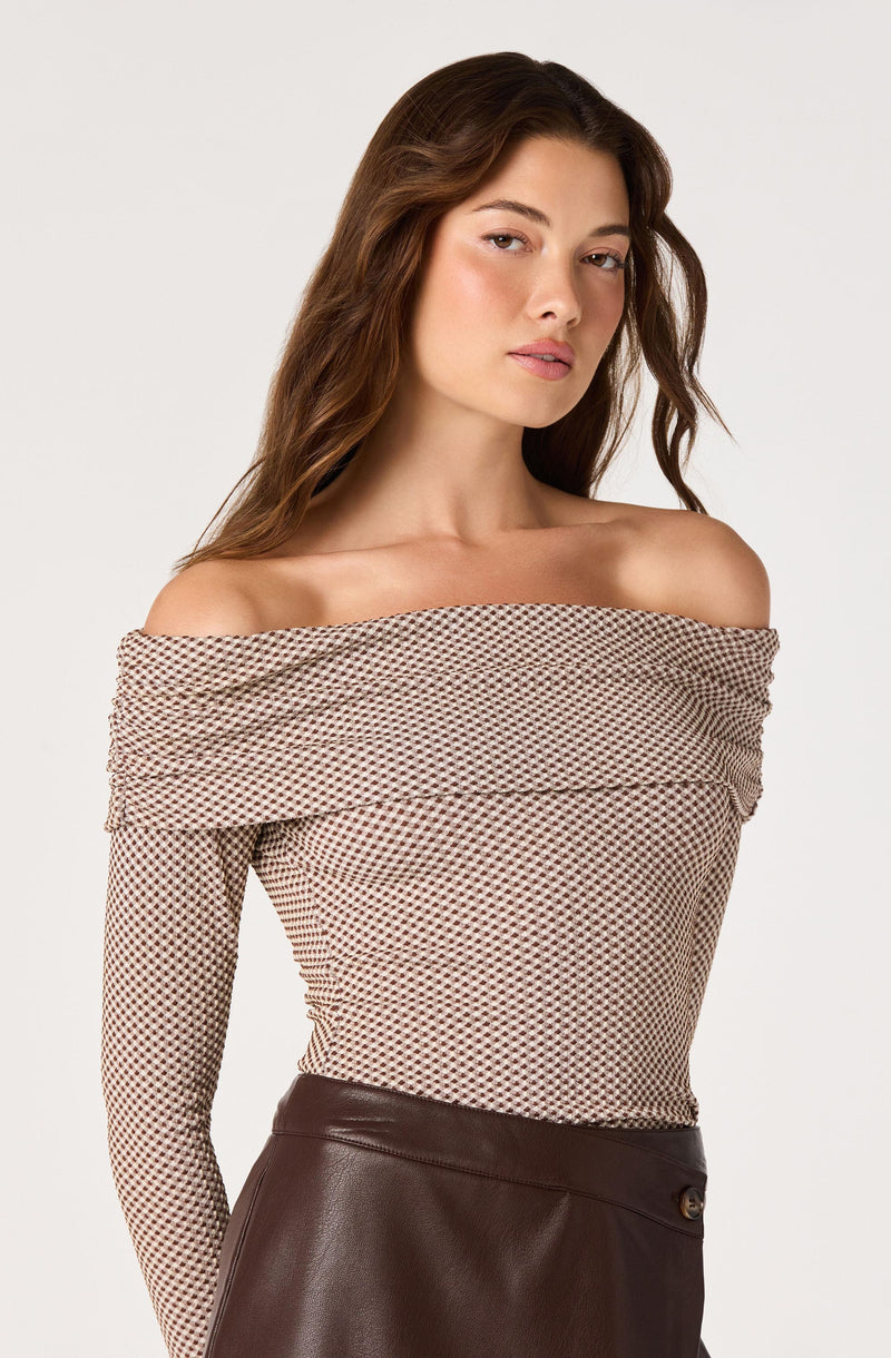 Off-the-shoulder patterned top with long sleeves and a leather skirt.
