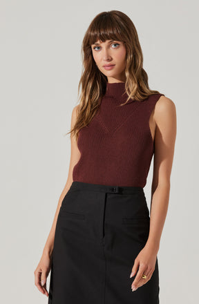 A woman is wearing a sleeveless, ribbed, high-neck top in a deep burgundy color with subtle vertical stripes and seam detailing on the front. She pairs it with a high-waisted black skirt that has a front button and two horizontal pocket flaps.