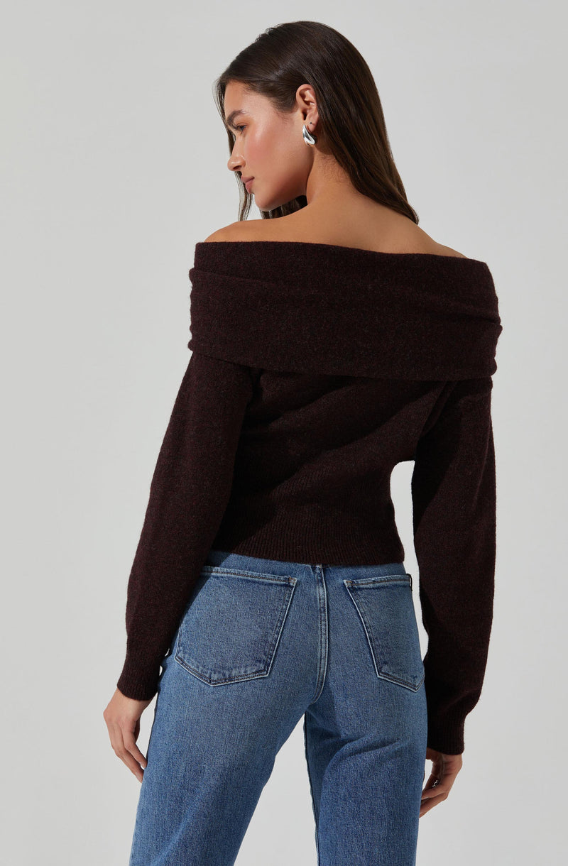 A woman is wearing an off-the-shoulder, long-sleeve sweater in a dark, rich brown color. The sweater appears to be made of a soft, knit fabric and features a wide neckline that drapes over her shoulders. She is also wearing medium-wash blue jeans with classic back pockets.