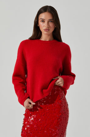A woman is wearing a bright red, long-sleeved, knitted sweater paired with a high-waisted red sequined skirt.