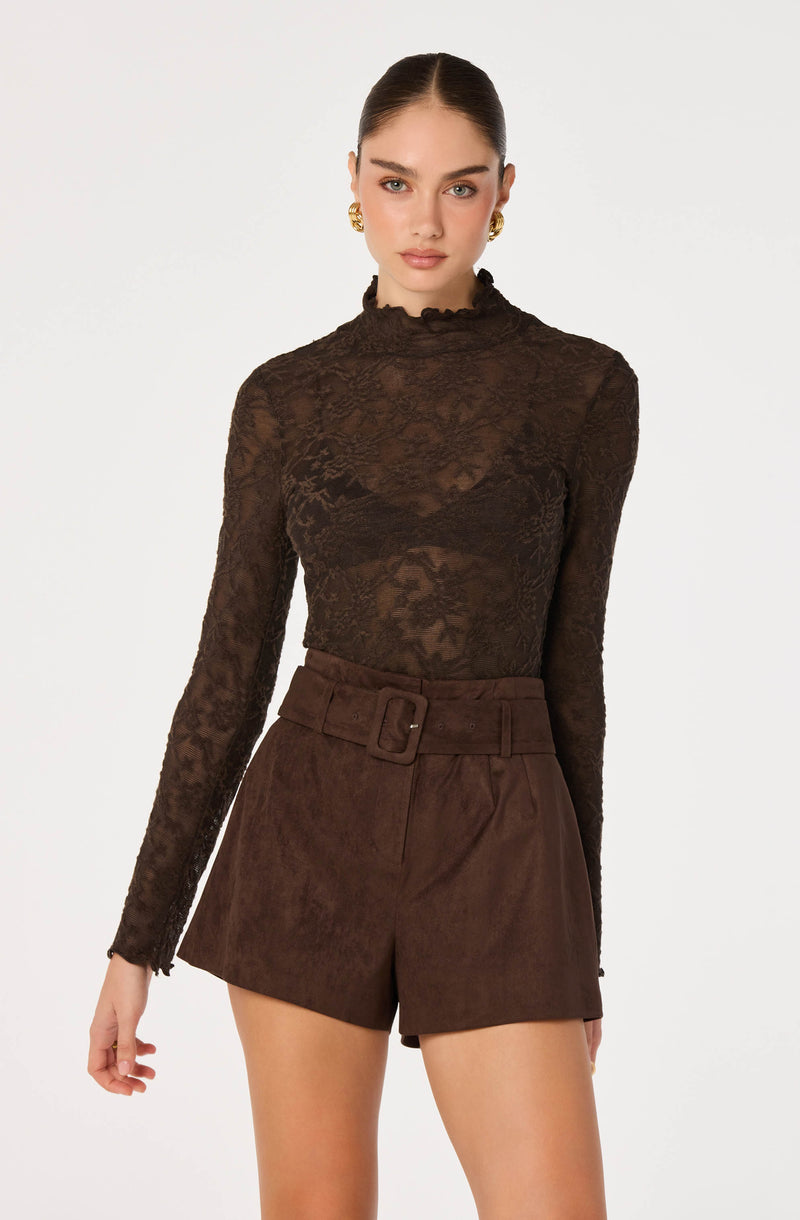 Model wearing a black lace long-sleeve top and high-waisted brown shorts with a belt.