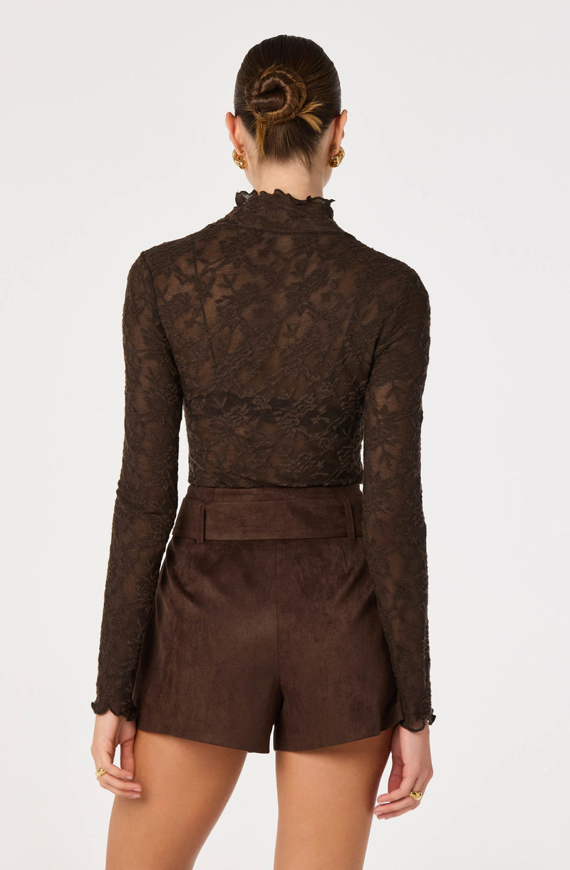 Woman in a sheer, long-sleeved chocolate lace top with a high neck, paired with matching brown shorts.