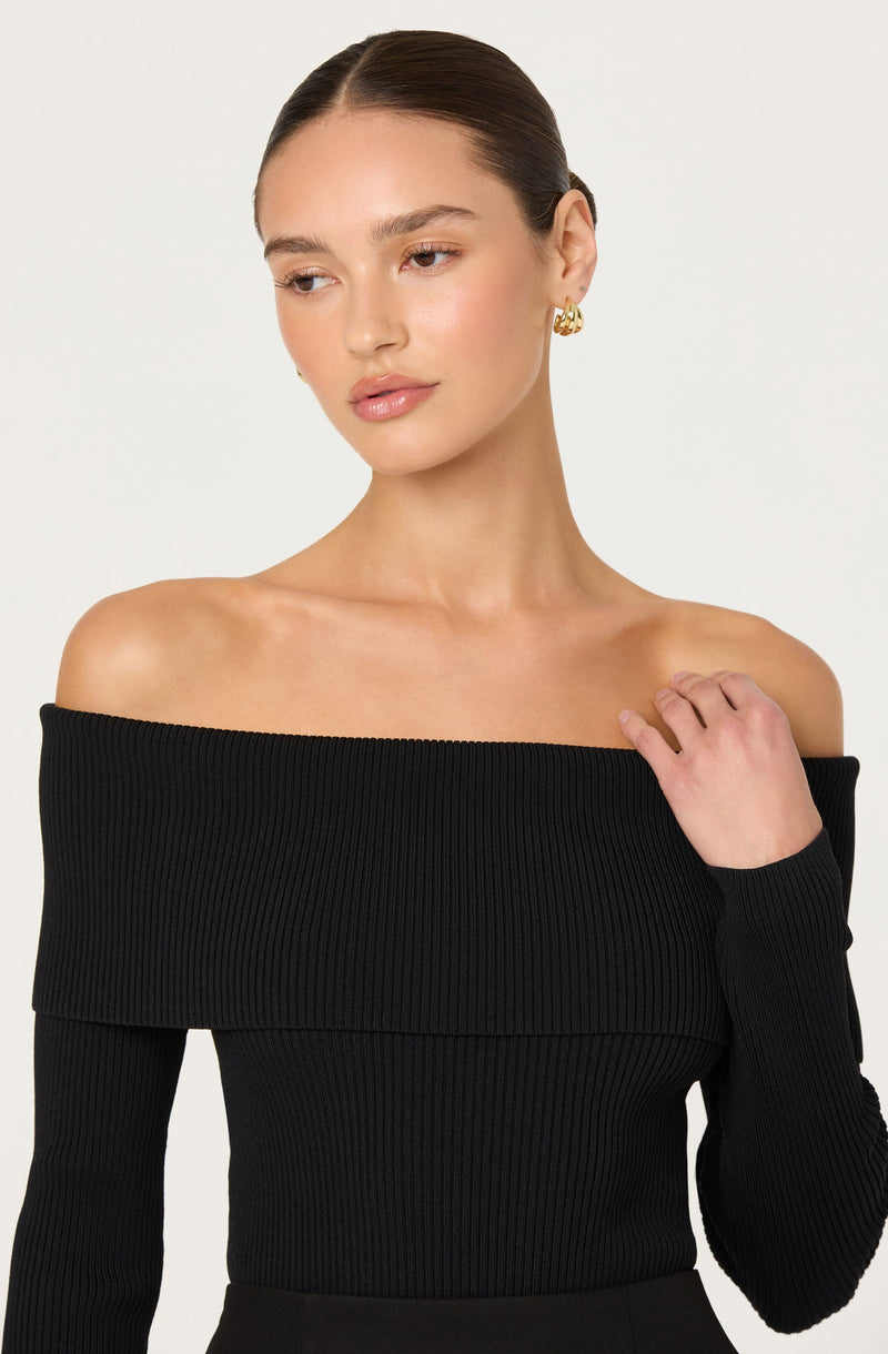 A woman is wearing a black, off-the-shoulder, ribbed knit top.