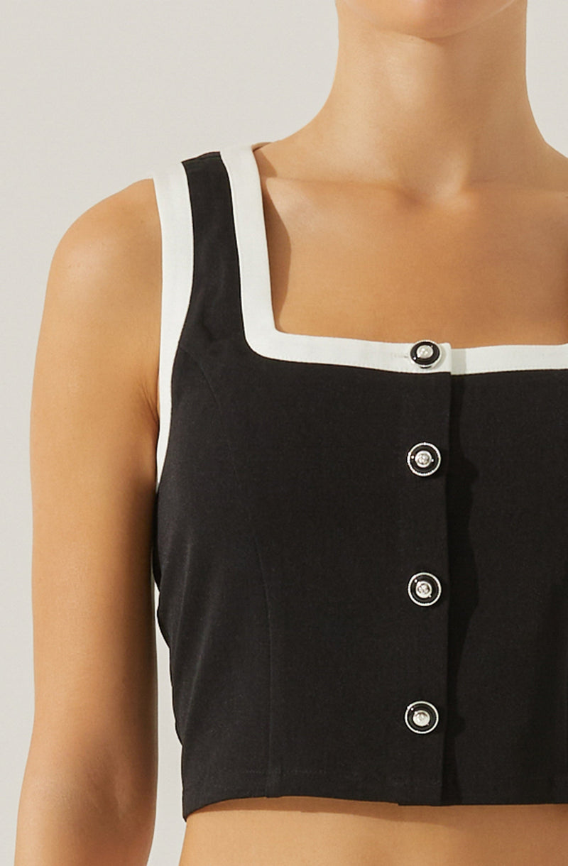 A sleeveless black crop top with white trim along the neckline and armholes. The top features a front button closure with shiny silver buttons.