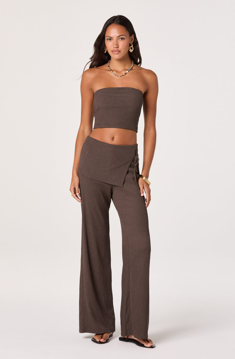 Woman in brown strapless top and wide-leg pants with a wrap detail.