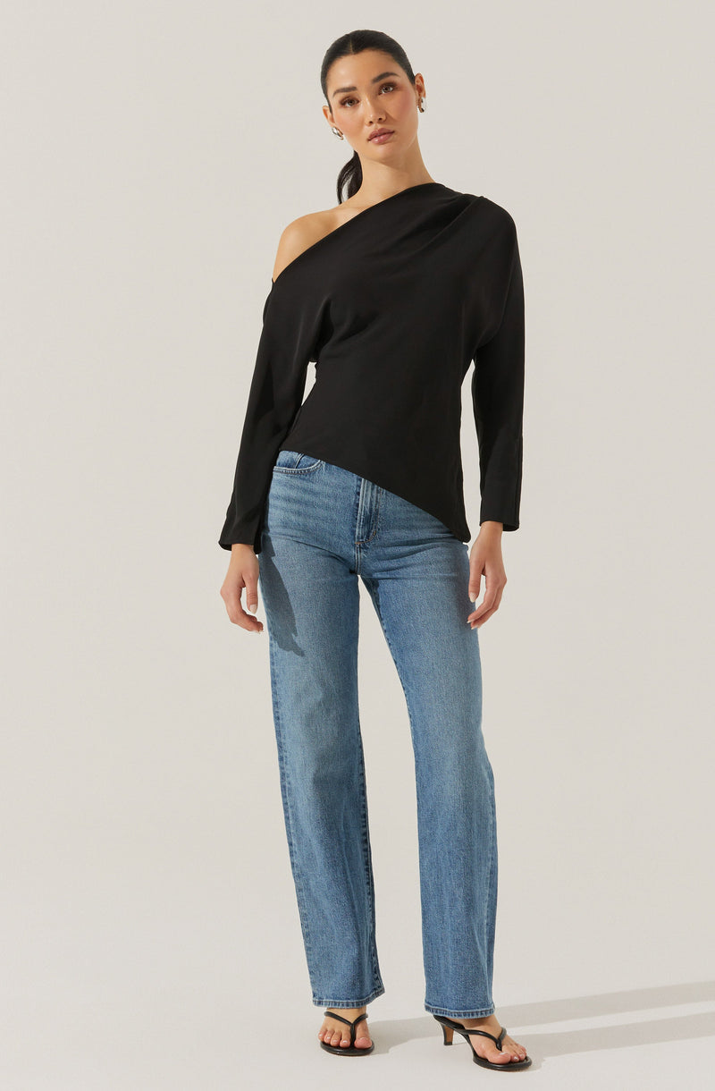 A woman is wearing a black, one-shoulder, long-sleeve blouse with a slightly loose fit. She pairs the top with light blue, high-waisted denim jeans that have a straight-leg cut. She completes the outfit with black, open-toe high-heeled sandals.