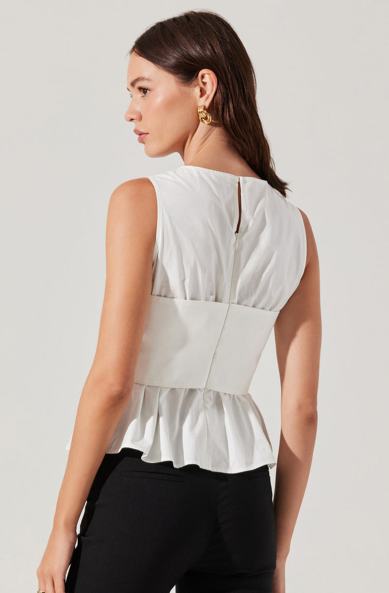 A woman is wearing a sleeveless white top with a high waist and a peplum hem. The top features a back zipper closure and a small slit at the upper back. She is also wearing large, gold, twisted hoop earrings.