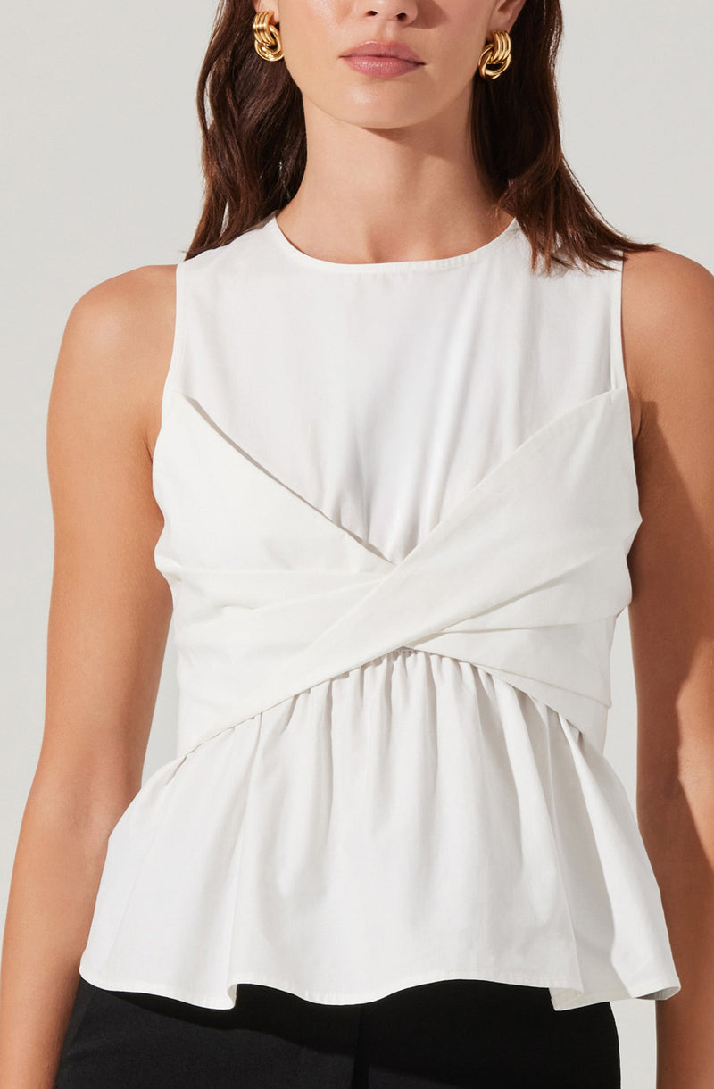 A woman is wearing a sleeveless white top with a round neckline. The top features a draped, layered design with pleats and gathered fabric around the waist, creating a peplum effect. The fabric appears smooth and slightly shiny. She is accessorized with large, gold hoop earrings.