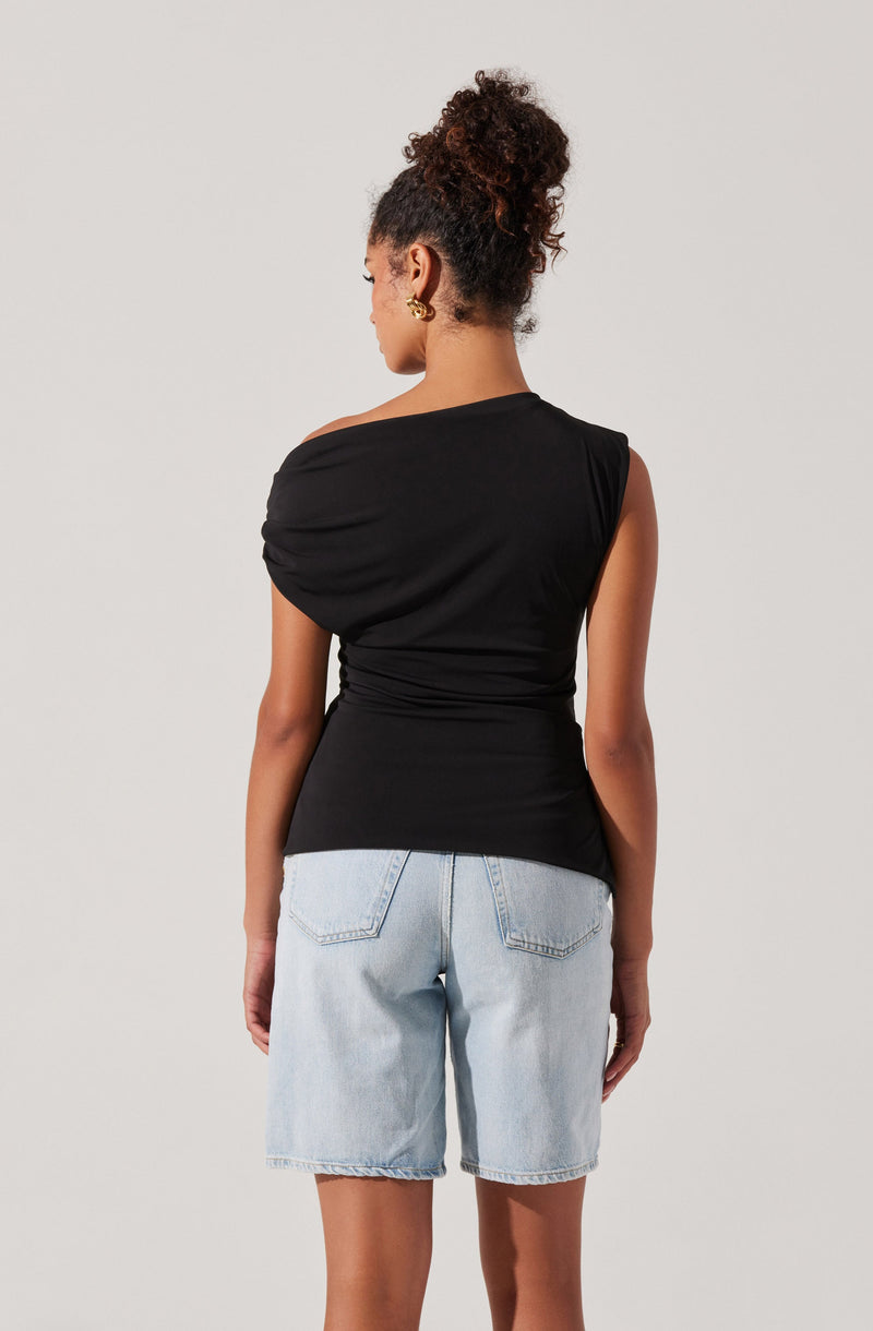 A woman is wearing a sleeveless black top with a draped, gathered design on one shoulder and fitted at the waist. She is also wearing light blue denim shorts with back pockets.